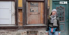 Bauforscherin vor einer Hauswand mit mehreren zugesetzten Holztüren
