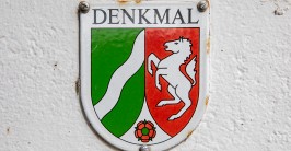 Emailleschild mit Wappen auf wei&szlig; gestrichener Wand