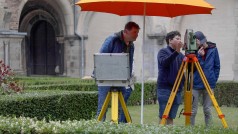 Vermessungsingenieur und Schüler mit einem ELTA, im Hintergrund der Seiteneingang zu einer Kirche