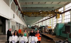 fünf Personen an Stehtischen im Inneren einer großen Industriehalle