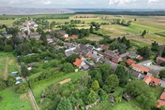 Luftaufnahme des Dorfes Morschenich mit Tagebau und Hambacher Forst im Hintergrund.