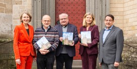 f&uuml;nf Personen, das Buch zum Xantener Dom in den H&auml;nden haltend, vor dem Dom St. Viktor