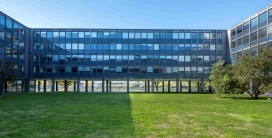 auf Stelzen gelagertes vierstöckiges Gebäude mit Fensterbändern und Flachdach