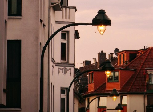 mehrere Gasleuchten spenden warmes Licht in der Abenddämmerung und leuchten einen Straßenzug aus