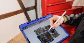 von Person gehaltenes Tablet mit digitalem Grundriss eines Fachwerkbaus
