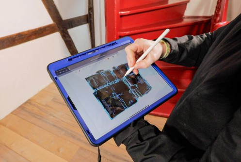 von Person gehaltenes Tablet mit digitalem Grundriss eines Fachwerkbaus