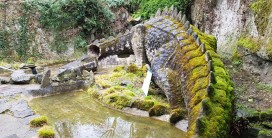 monumentale Drachenskulptur mit abgebrochenem Kopf an einem Teich