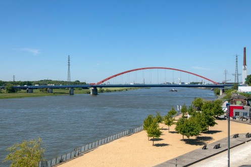 sich &uuml;ber einen breiten Fluss spannende, von Autos befahrene Bogenbr&uuml;cke