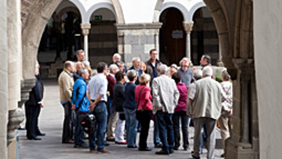 Durchblick in den romanischen Kreuzgang der Abtei Brauweiler auf eine Besuchergruppe mit Führendem