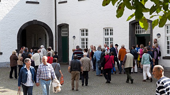 wandelnde Besucherinnen und Besucher im Wirtschaftshof der Abtei Brauweiler