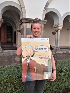 Junge Frau hält Plakat, auf dem Willi Spürnase zu sehen ist. 